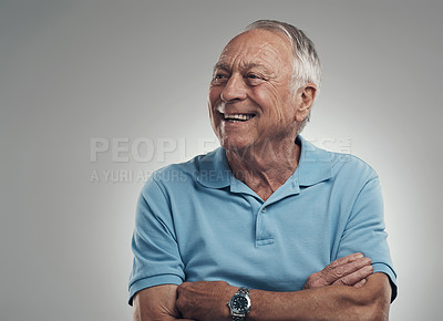 Buy stock photo Shot of an older man with his arms crossed looking off into the distance in a studio against a grey background