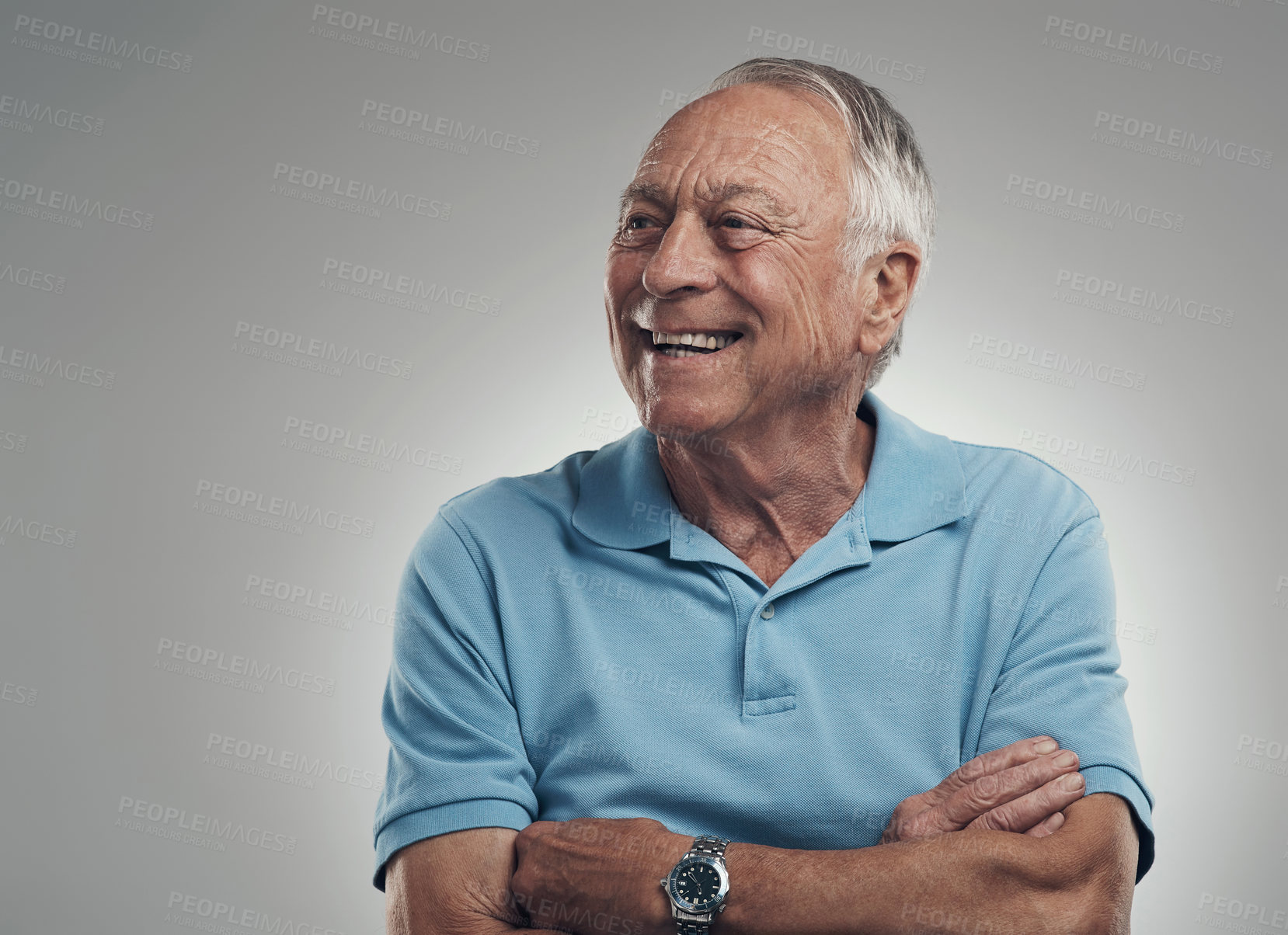 Buy stock photo Shot of an older man with his arms crossed looking off into the distance in a studio against a grey background