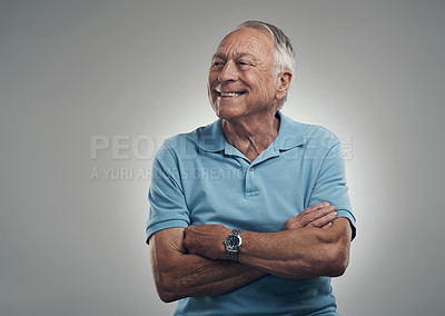 Buy stock photo Shot of an older man with his arms crossed looking off into the distance in a studio against a grey background