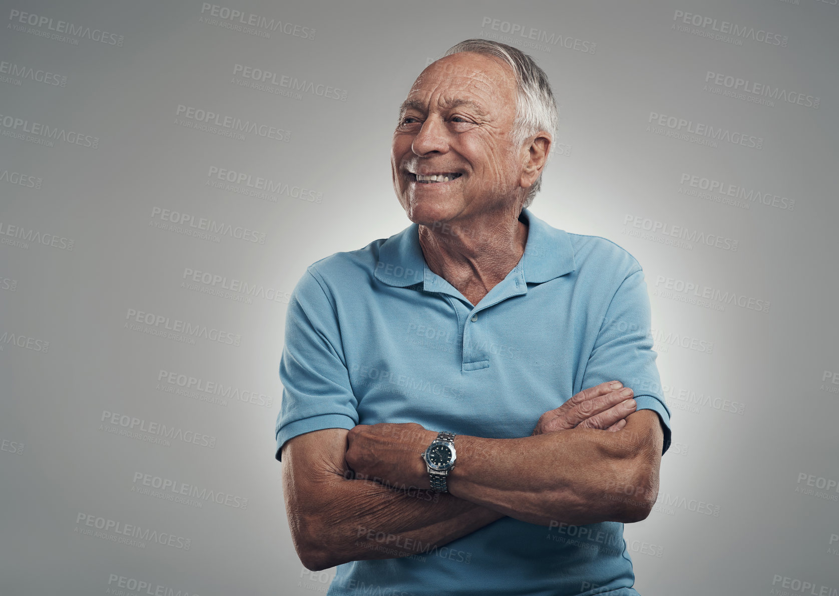 Buy stock photo Shot of an older man with his arms crossed looking off into the distance in a studio against a grey background