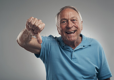 Buy stock photo Shot of a happy older man giving the thumbs down in a studio against a grey background