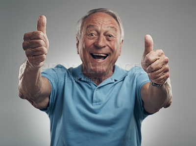 Buy stock photo Shot of a happy elderly man giving the thumbs up in a studio against a grey background