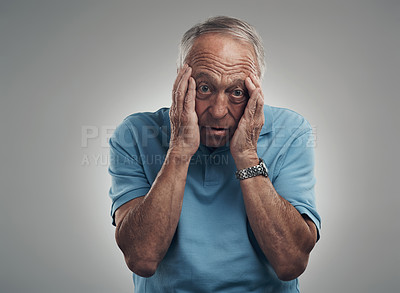 Buy stock photo Shot of an elderly man clasping his hands to his face in a studio against a grey background