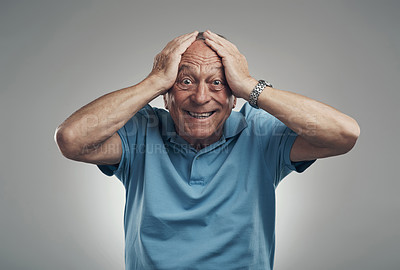 Buy stock photo Shot of an older man with his hands on his head in shock in a studio against a grey background