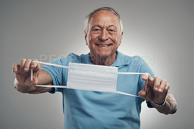 Buy stock photo Shot of an elderly man holding a protective face mask in a studio agains a grey background