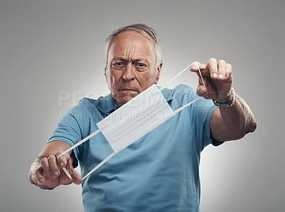 Buy stock photo Shot of an elderly man holding a protective face mask in a studio agains a grey background