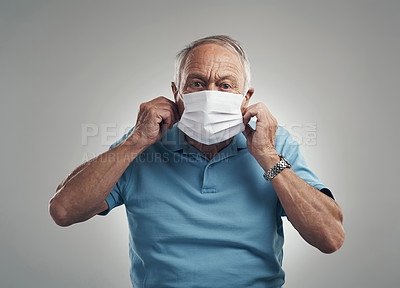 Buy stock photo Shot of an older man wearing a protective face mask in a studio against a grey background