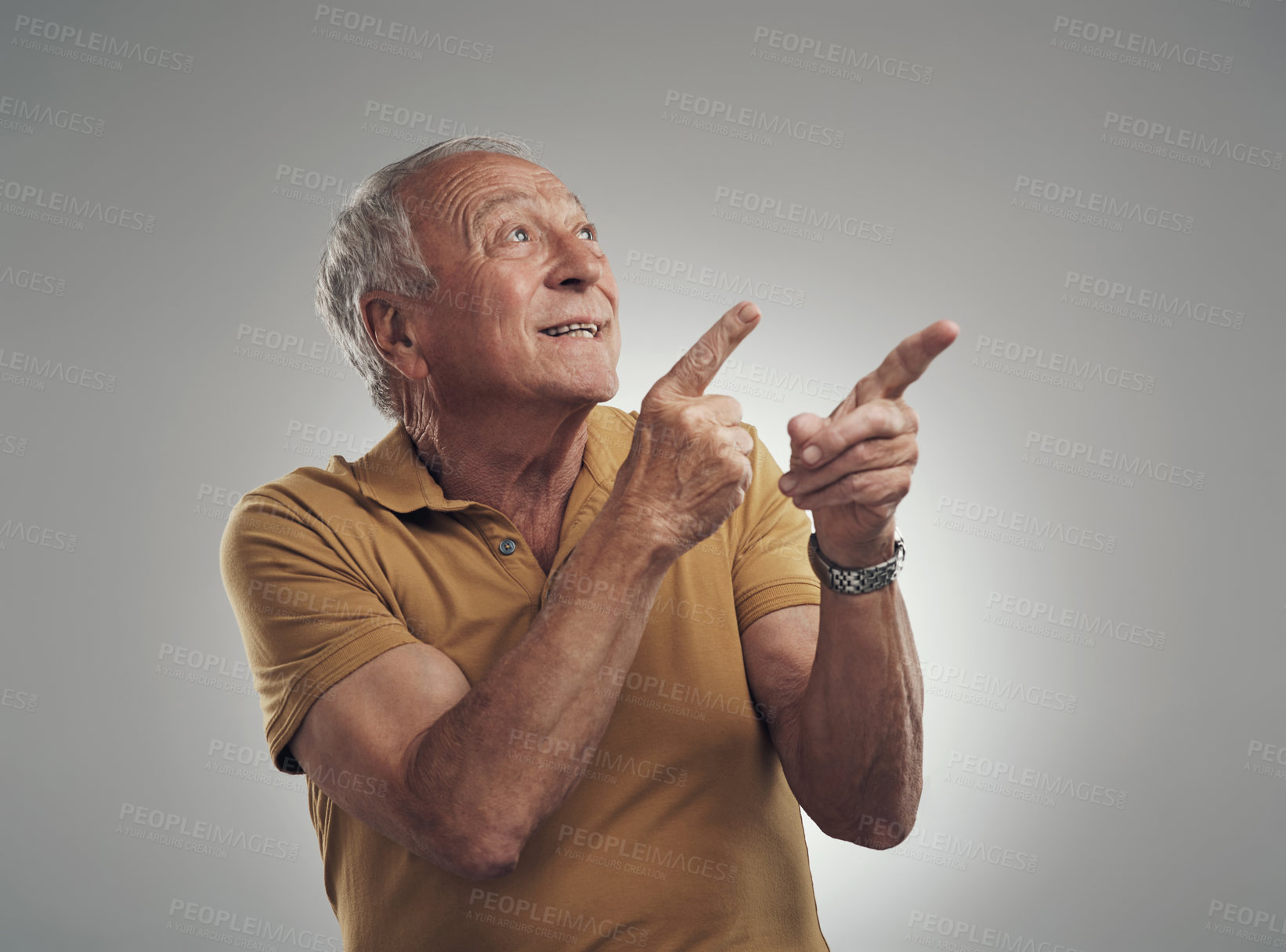 Buy stock photo Studio shot of an elderly man pointing in at something and smiling against a grey background