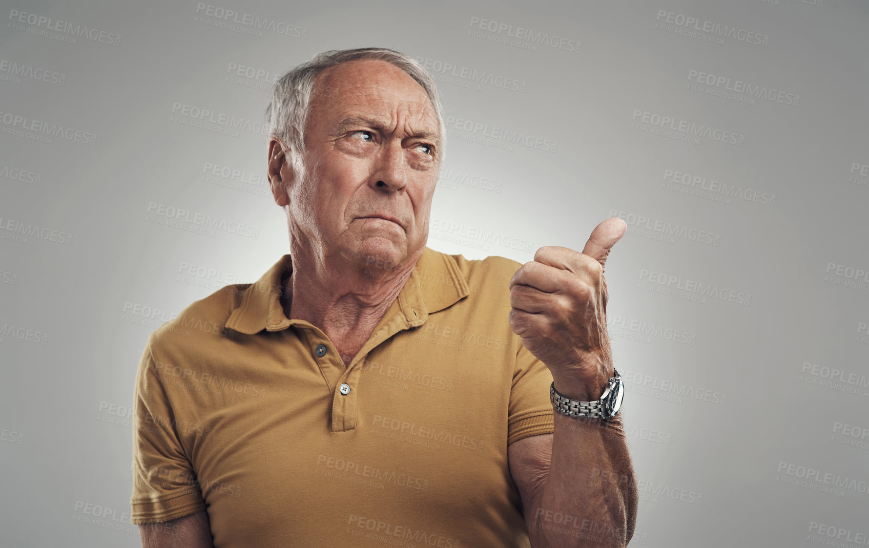 Buy stock photo Studio shot of an elderly man pointing in at something against a grey background