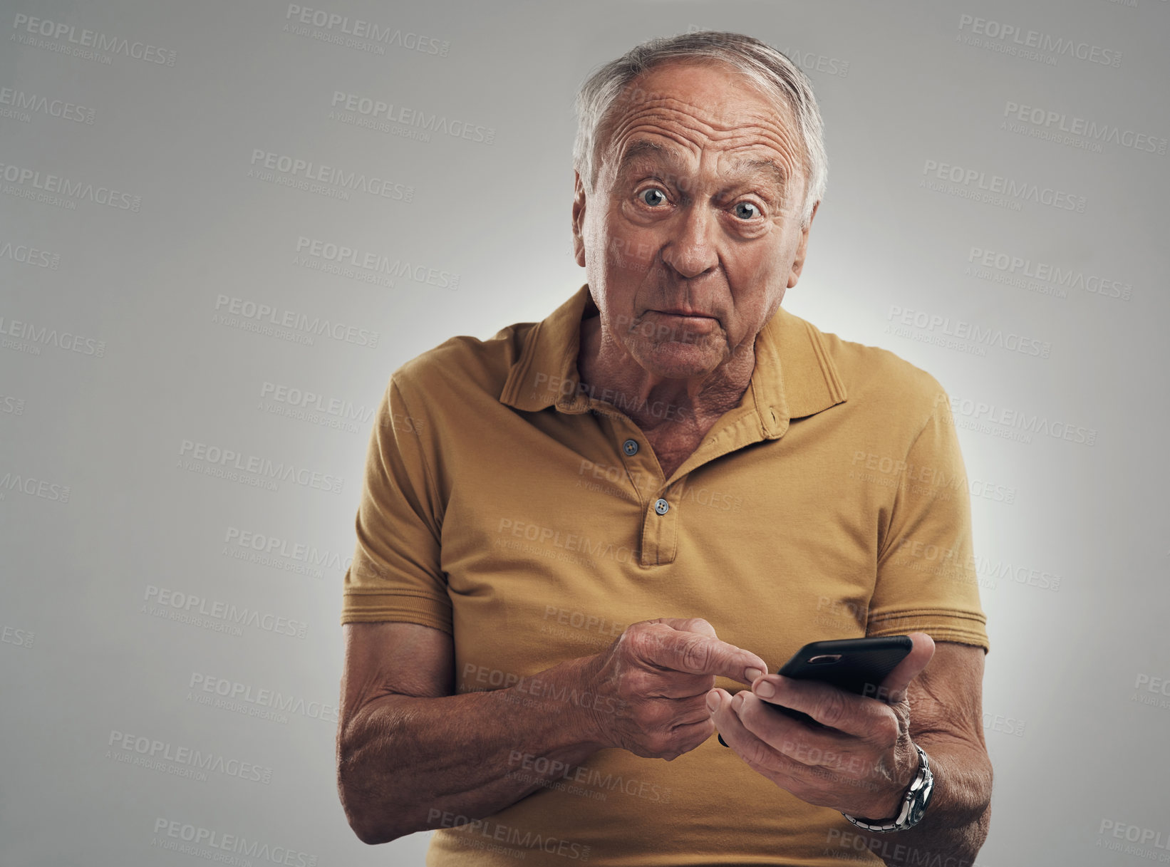 Buy stock photo Studio shot of an elderly man using his cellphone against a grey background