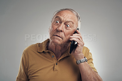 Buy stock photo Studio shot of an elderly man using his cellphone against a grey background