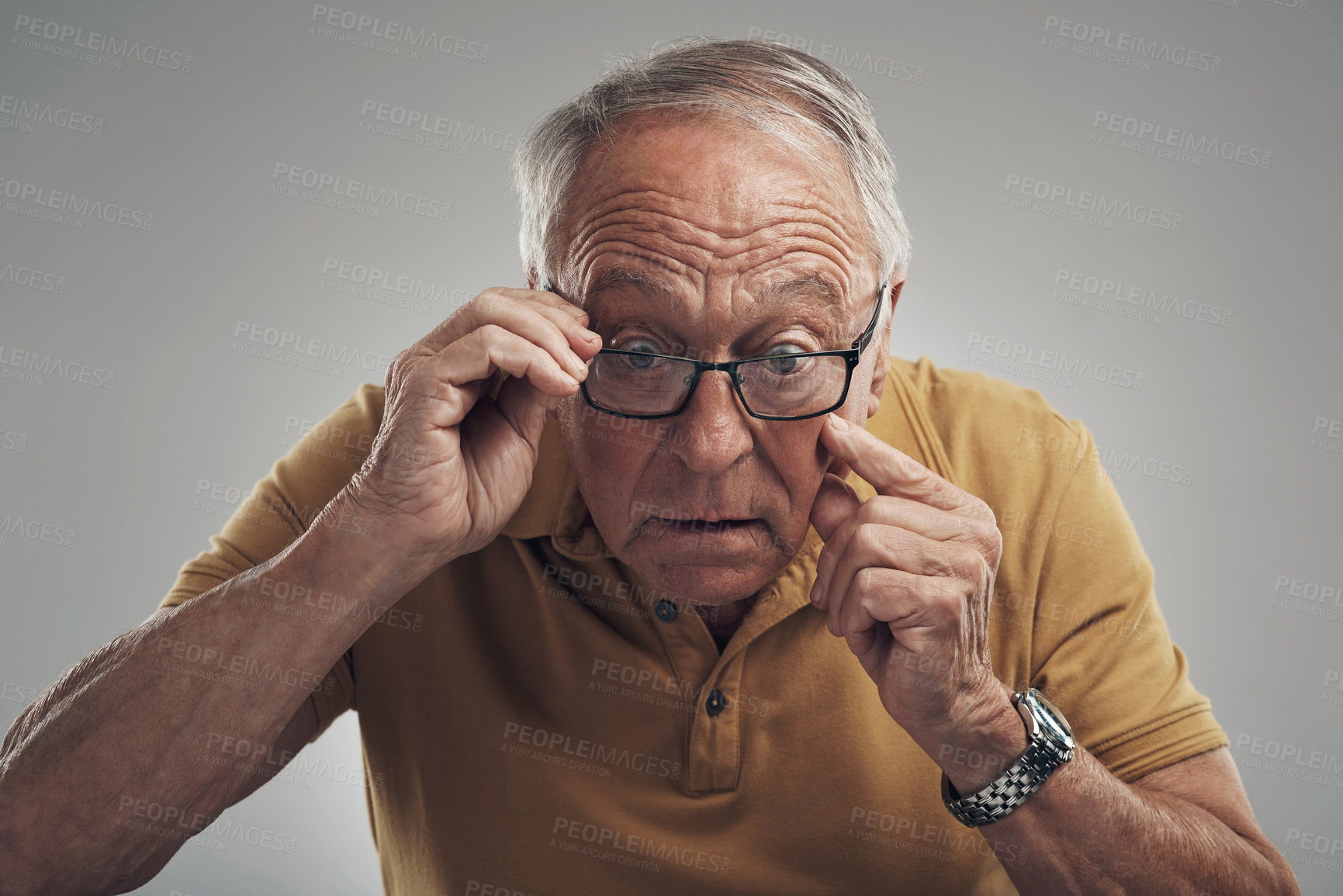 Buy stock photo Studio shot of an elderly man adjusting his spectacles against a grey background