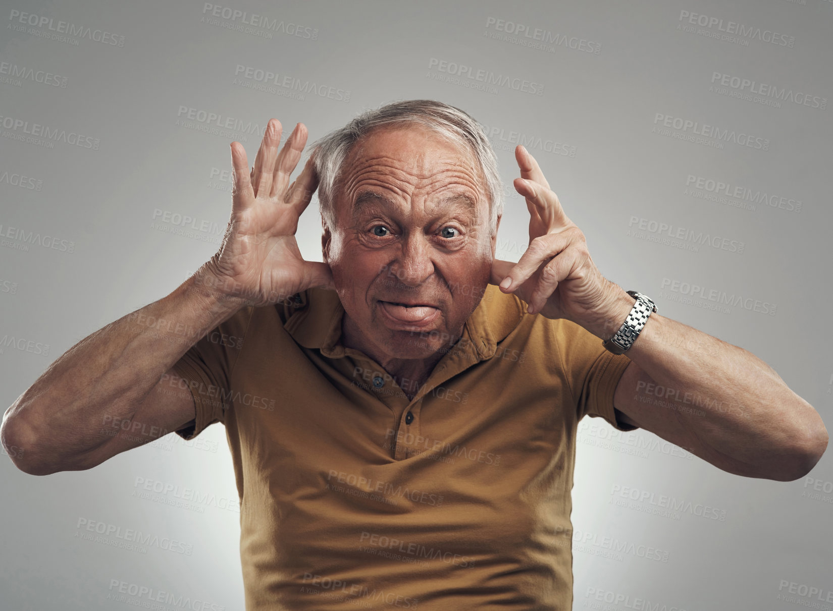 Buy stock photo Studio shot of an elderly man making a funny face against a grey background