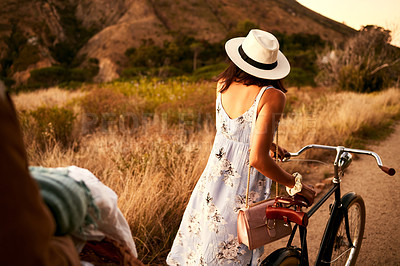 Buy stock photo Shot of a unrecognizable woman walking with a bike outside in nature