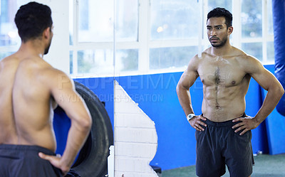 Buy stock photo Shot of s young man analysing his body in the mirror at his gym