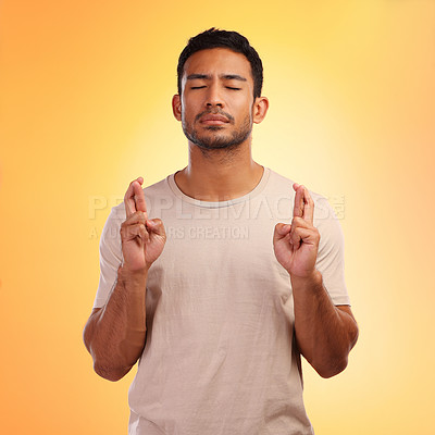Buy stock photo Fingers crossed, wish and man model with orange studio background and hope. Optimism, eyes closed and modern person with a beard hoping for good luck of a young casual male with a tshirt isolated 