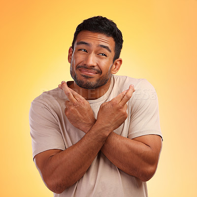Buy stock photo Fingers crossed, man and model with a orange studio background with hand sign for luck. Smile, hope and faith of a person with beard holding hands gesture for wish and optimism feeling hopeful