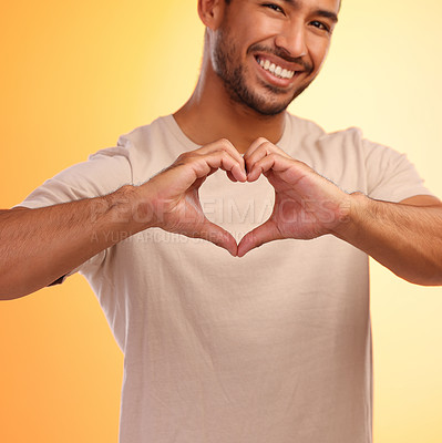 Buy stock photo Portrait, heart and hands of man in studio isolated on a yellow background. Love, romance and happy male model with hand gesture for romantic emoji, care symbol or kindness, support or thank you.