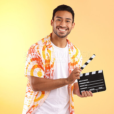 Buy stock photo Portrait, clapper board and man in studio isolated on a yellow background. Director, film production and happy male model in stylish or cool tie dye shirt holding clapperboard to cut scenes in movies