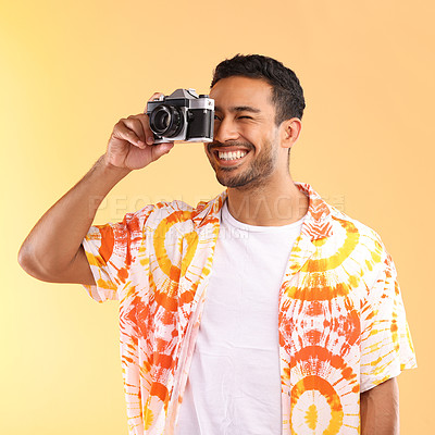 Buy stock photo Photographer, camera and man taking pictures in studio isolated on an orange background. Travel, vacation and male model holding camcorder technology for taking photo for happy memory on holiday.