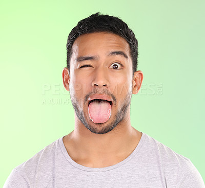 Buy stock photo Man, portrait and silly in studio, tongue and goofy comic or funny face on green background. Male person, mockup space and wink for joke or comedy, student and humor for crazy character and emoji