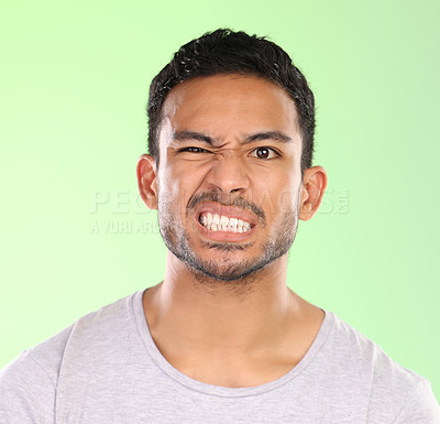 Buy stock photo Man, portrait and angry face with disgust for awkward humor or funny humor on a green studio background. Frustrated male person or joker with goofy expression, attitude or upset behavior in anger