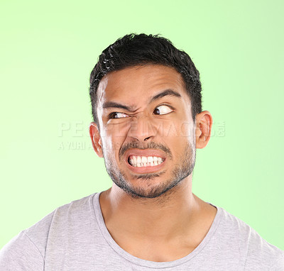 Buy stock photo Man, angry face and disgust with awkward humor, comedy or nasty look on a green studio background. Frustrated male person or joker with goofy expression, attitude or upset behavior for wild anger
