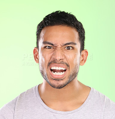 Buy stock photo Angry man, portrait and face with emotion for frustration, moody or irritated on a green studio background. Frustrated male person with anger, crazy expression or negative attitude and upset behavior