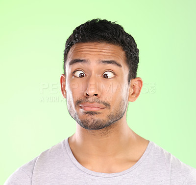 Buy stock photo Man, funny face and silly in studio, crosses eyes and goofy comic or humor on green background. Male person, mockup space and emoji for joke or comedy, student and play a crazy or quirky character