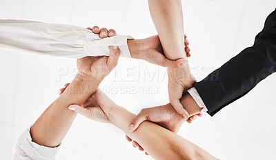 Buy stock photo Low angle shot of a group of businesspeople holding one another's wrists in a circular formation