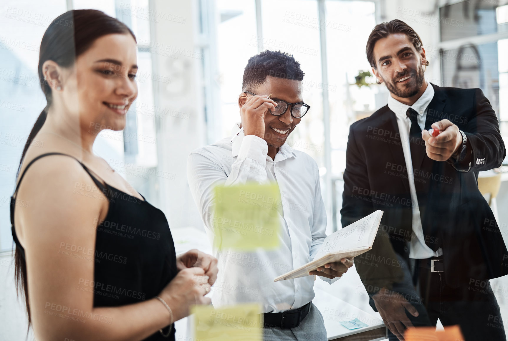 Buy stock photo Shot of a group of businesspeople brainstorming with notes on a glass wall in an office