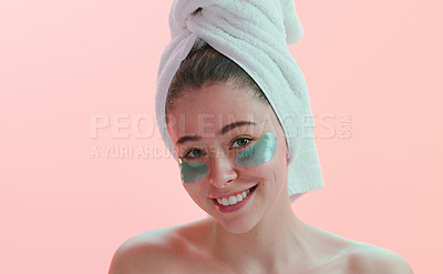 Buy stock photo Studio portrait of a young woman smiling with an eye treatment on her face against a pink background