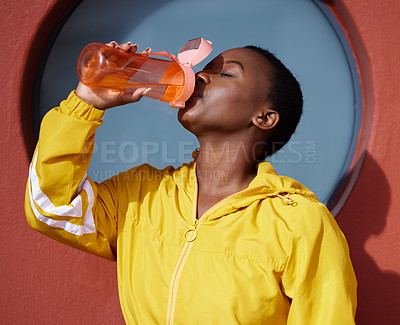 Buy stock photo Shot of a young woman drinking water after her workout against an urban background