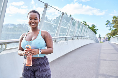 Buy stock photo Shot of a young woman holding a water bottle during a workout against an urban background