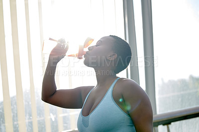 Buy stock photo Shot of a young woman drinking water after her workout against an urban background