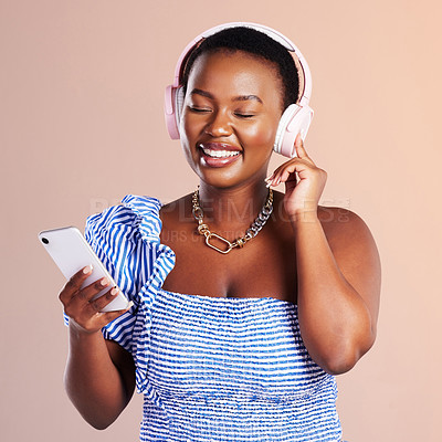 Buy stock photo Black woman, headphones and smartphone for streaming music, happy and enjoying playlist on pink background. Listening to radio, podcast or audio online, wireless technology and mobile app for kpop