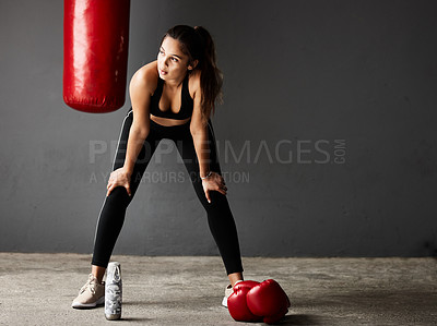 Buy stock photo Full length shot of an attractive young female boxer looking tired while training in the gym