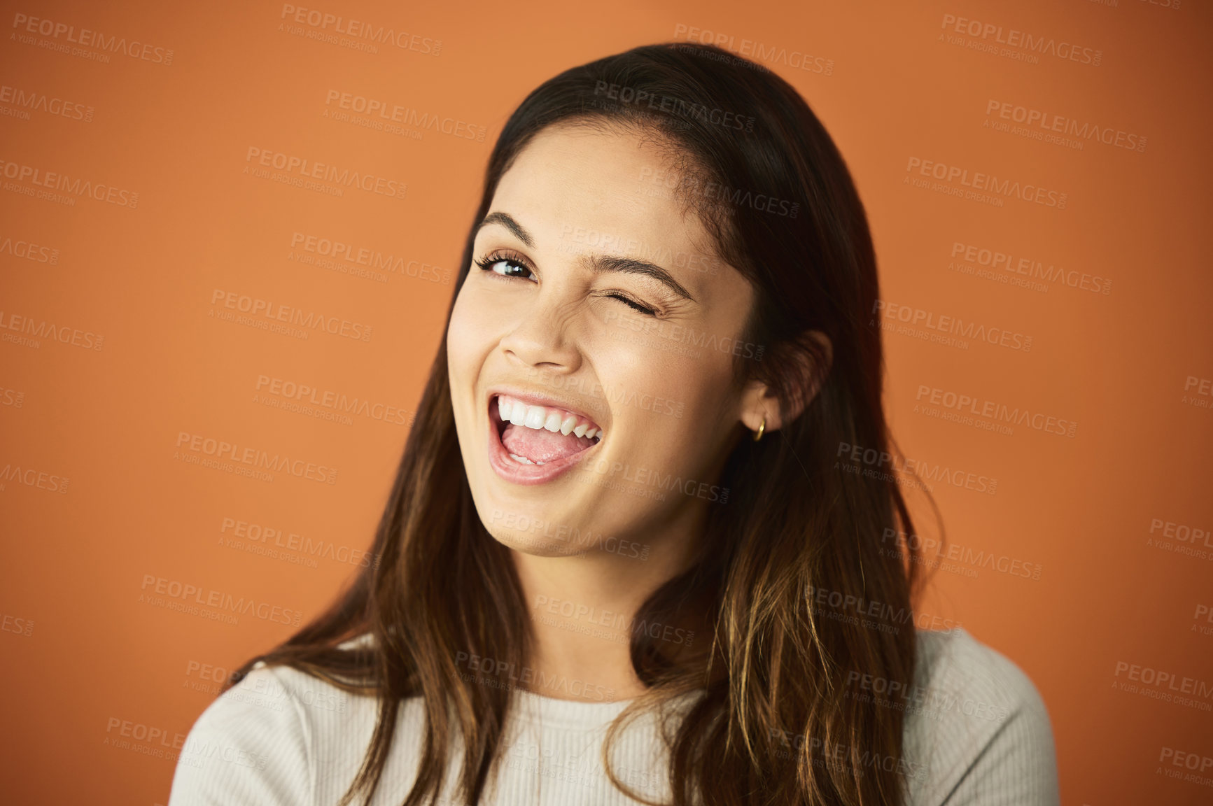 Buy stock photo Cropped portrait of an attractive young woman posing in studio against an orange background