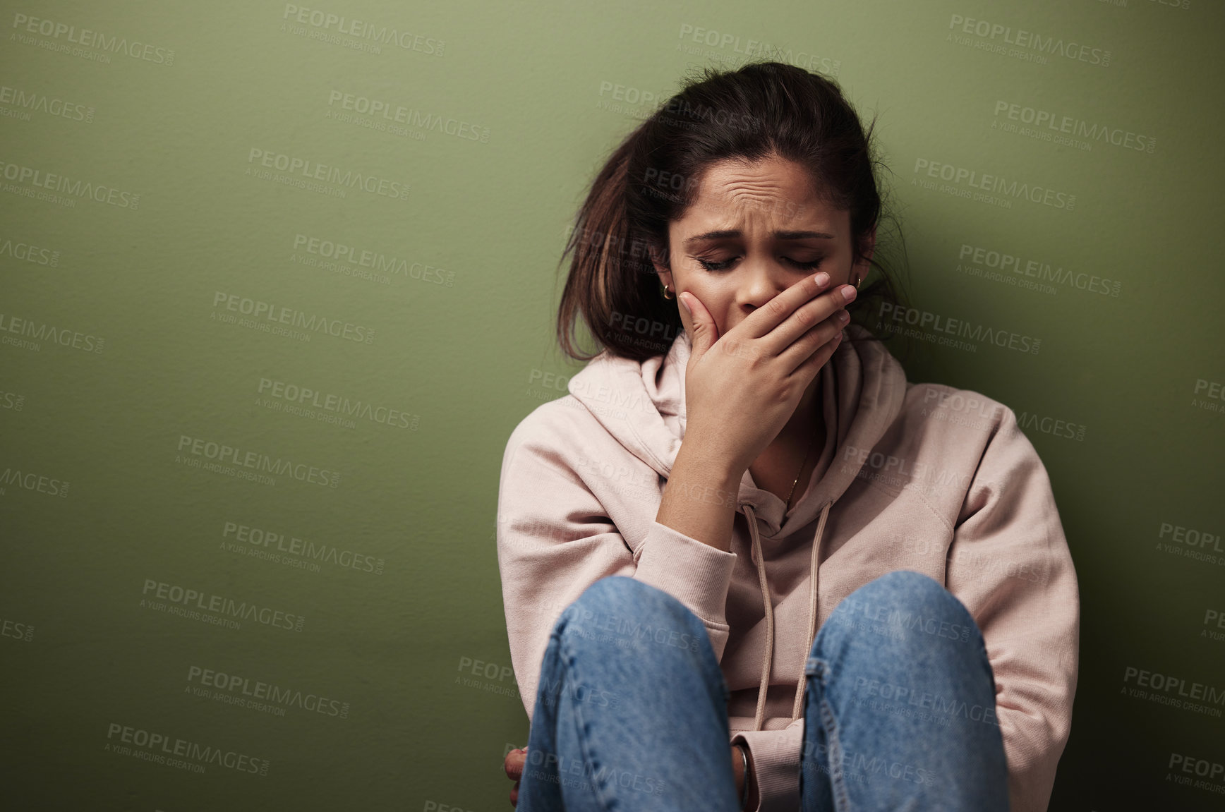 Buy stock photo Cropped shot of an attractive young woman crying against a green background