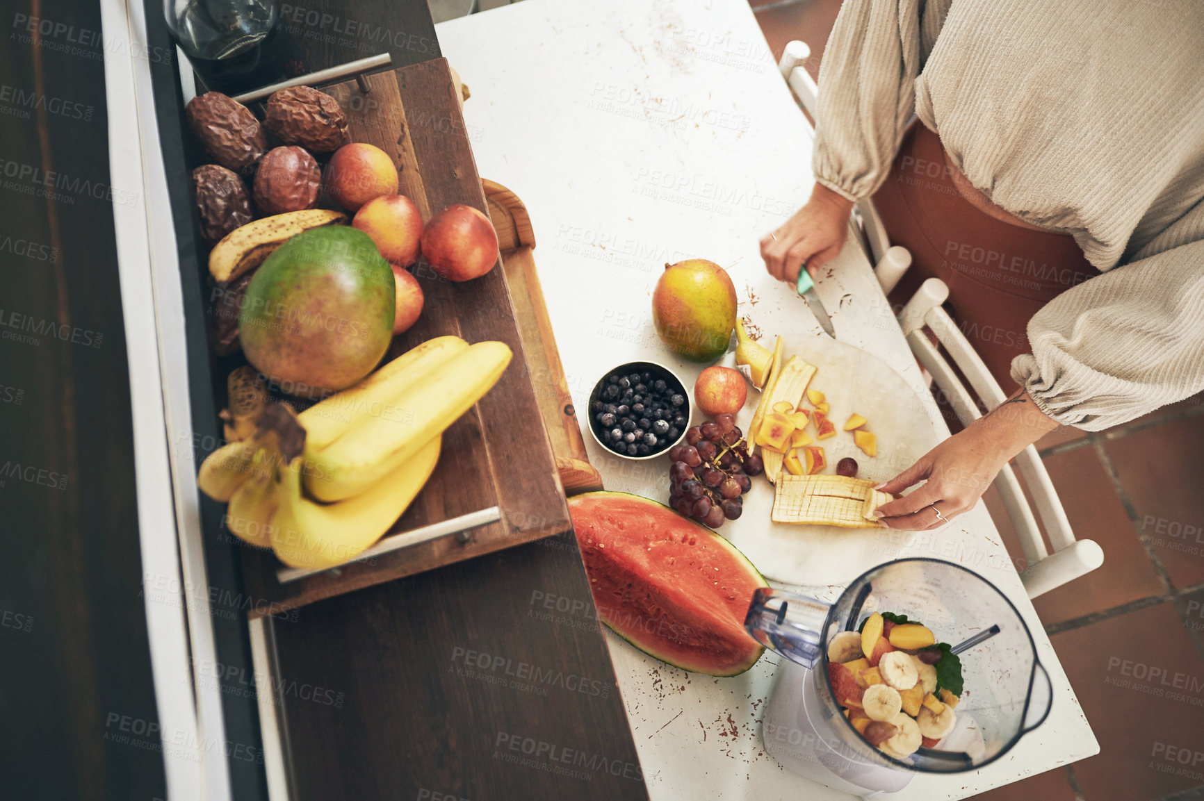 Buy stock photo Shot of a woman cutting up fruit for a smoothie