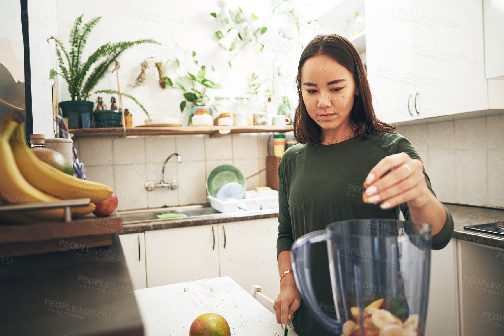 Buy stock photo Shot of a young woman preparing a smoothie at home