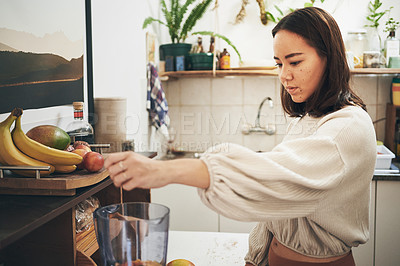 Buy stock photo Shot of a young woman using her blender to make a smoothie