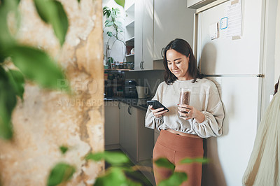 Buy stock photo Shot of a young woman using her smartphone while drinking a smoothie