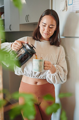 Buy stock photo Shot of a young woman pouring herself a cup of coffee