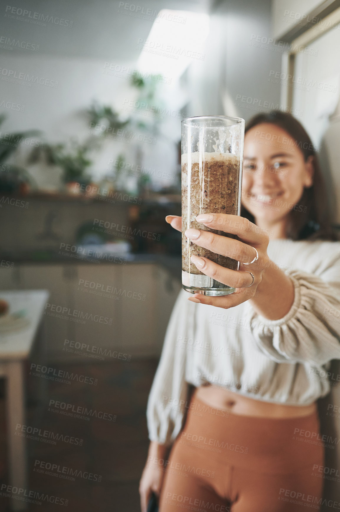 Buy stock photo Shot of a young woman holding her smoothie before drinking it..