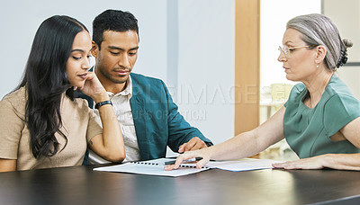 Buy stock photo Cropped shot of a young couple going over some paperwork during a meeting with their financial advisor