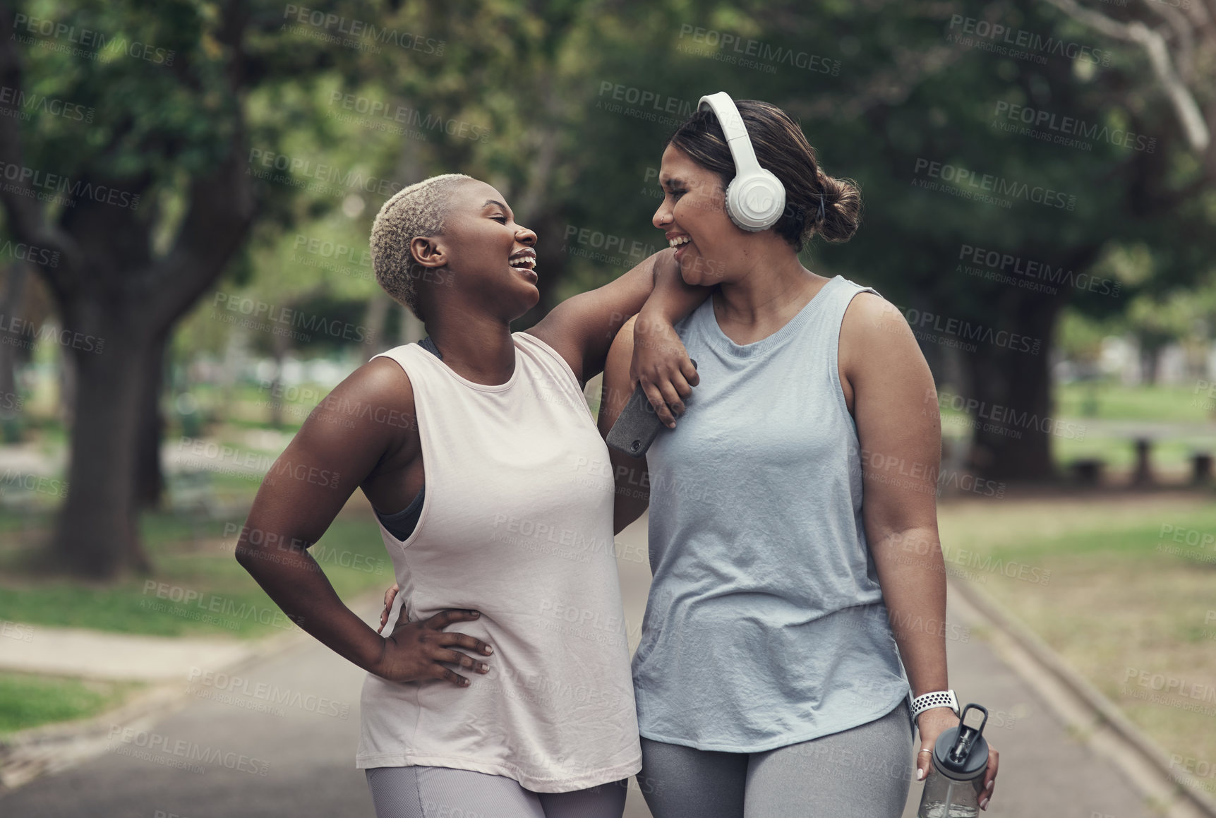 Buy stock photo Shot of two young woman taking a break during their workout