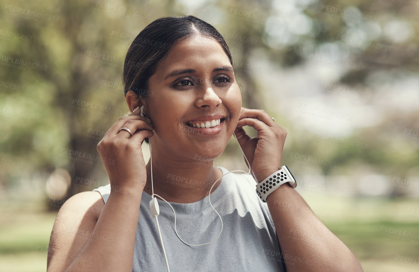 Buy stock photo Shot of a young woman using her earphone to listen to music during a workout