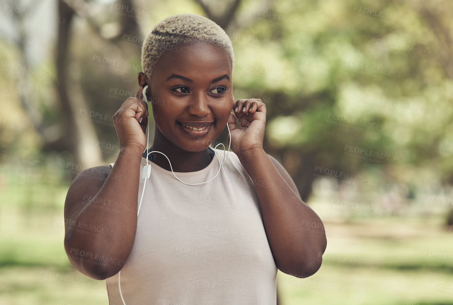 Buy stock photo Shot of a young woman using her earphone to listen to music during a workout