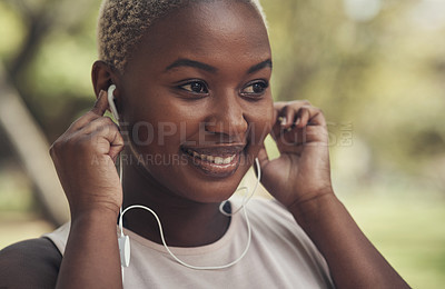 Buy stock photo Shot of a young woman using her earphone to listen to music during a workout